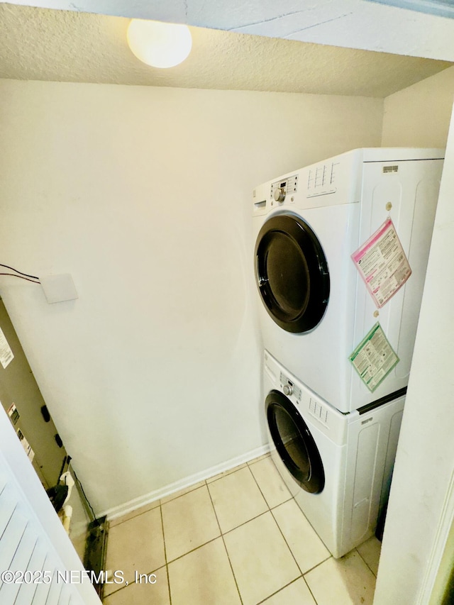 washroom with stacked washing maching and dryer and light tile patterned floors