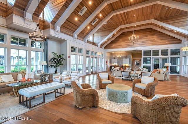 living area featuring visible vents, high vaulted ceiling, wood finished floors, an inviting chandelier, and wooden ceiling