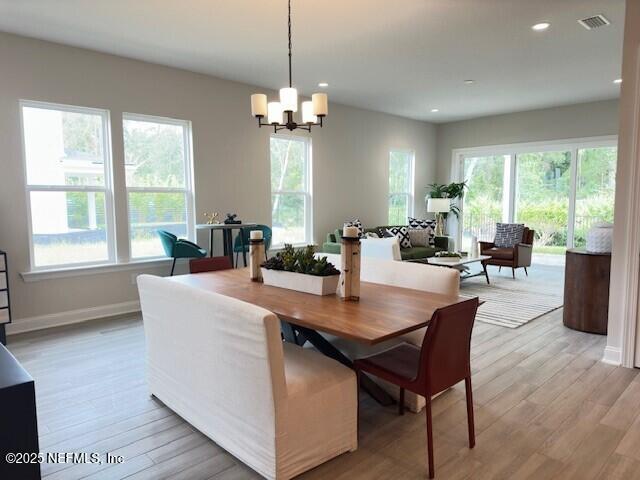 dining area featuring light wood-type flooring, visible vents, plenty of natural light, and a notable chandelier