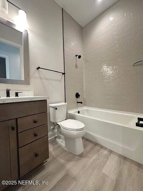 bathroom with vanity, wood finished floors, baseboards, toilet, and shower / bathtub combination