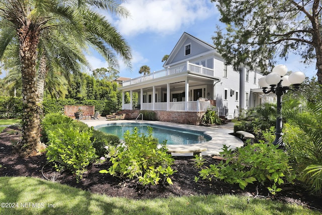 rear view of property with ceiling fan, a balcony, and a patio area