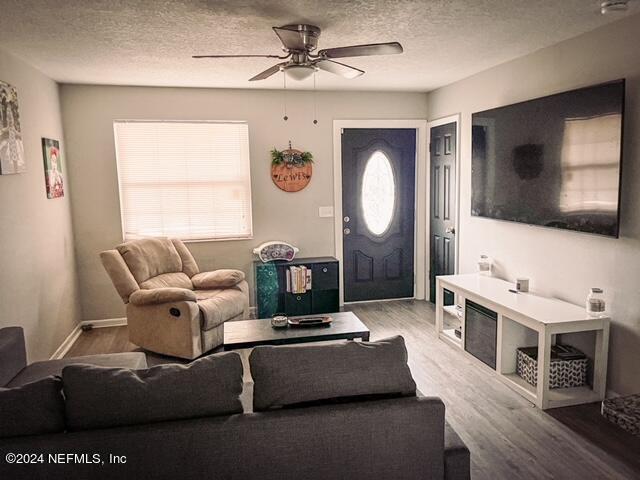 living room featuring a textured ceiling, ceiling fan, and hardwood / wood-style flooring