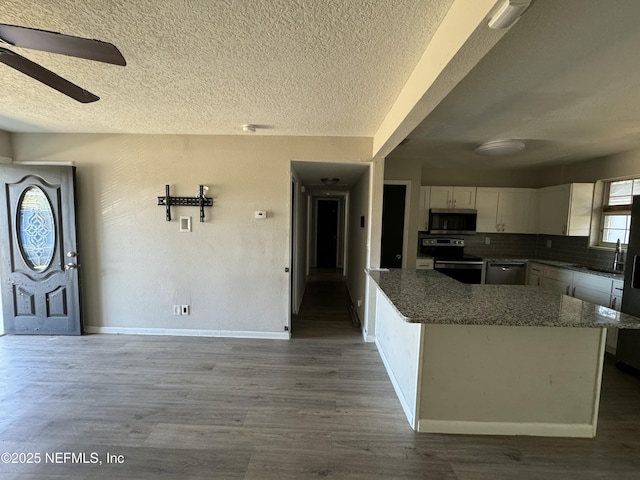 kitchen with stainless steel appliances, white cabinets, tasteful backsplash, wood-type flooring, and a kitchen island