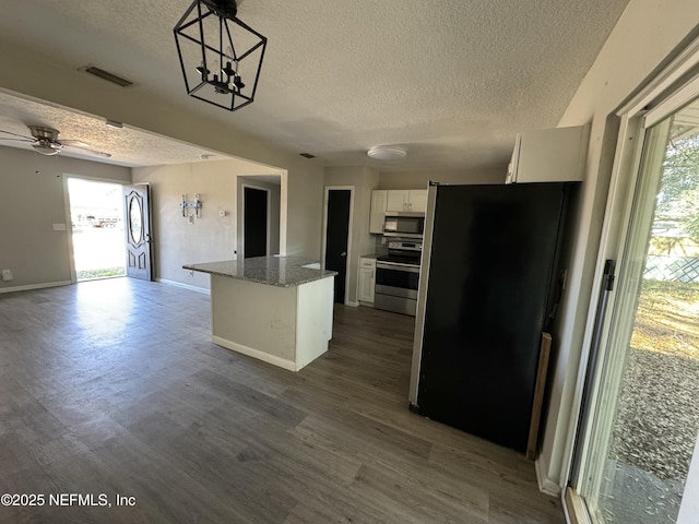 kitchen featuring light stone countertops, a center island, decorative light fixtures, white cabinetry, and appliances with stainless steel finishes