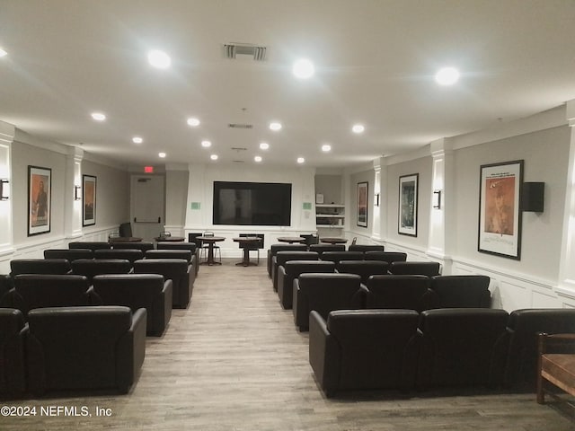 cinema featuring ornate columns, light wood-type flooring, and ornamental molding