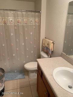 bathroom featuring a shower with curtain, vanity, toilet, and tile patterned floors