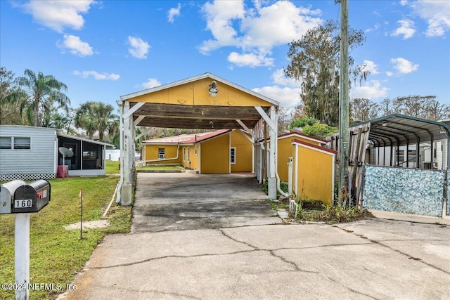 view of front of property featuring concrete driveway, a carport, and a front yard