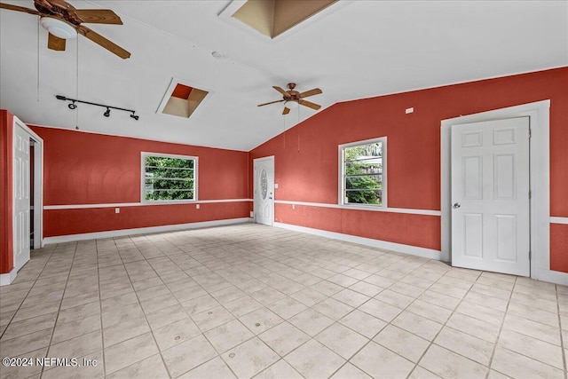 spare room featuring a ceiling fan, a healthy amount of sunlight, vaulted ceiling, and baseboards