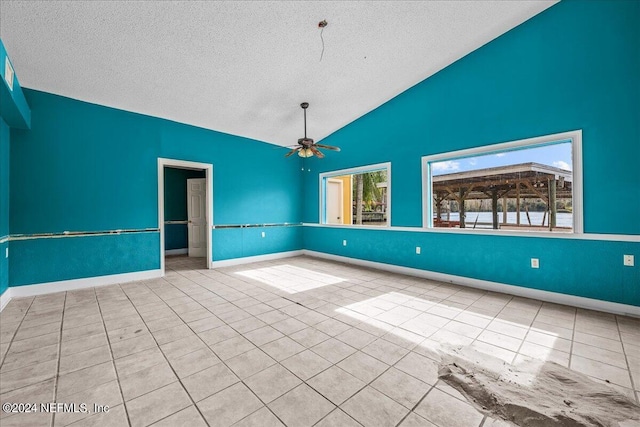 empty room featuring light tile patterned floors, baseboards, a ceiling fan, lofted ceiling, and a textured ceiling