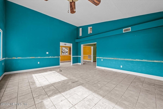 empty room featuring visible vents, ceiling fan, a textured ceiling, baseboards, and tile patterned floors