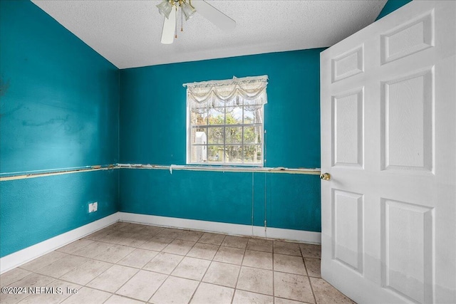 spare room with a ceiling fan, a textured ceiling, baseboards, and light tile patterned floors