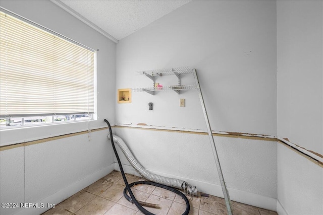 washroom with hookup for a washing machine, hookup for an electric dryer, light tile patterned flooring, a textured ceiling, and laundry area