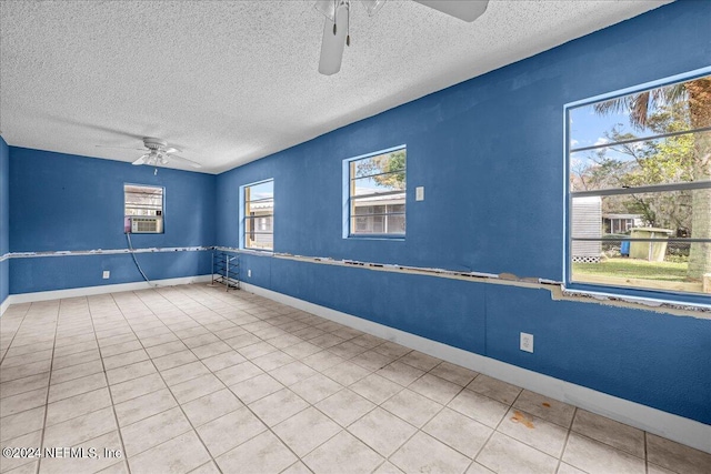 tiled empty room with a ceiling fan, cooling unit, a textured ceiling, and baseboards