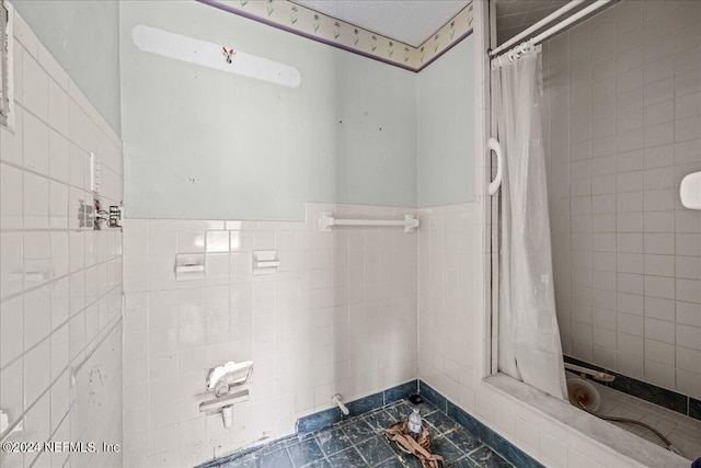 bathroom featuring a wainscoted wall, a tile shower, tile walls, and tile patterned floors