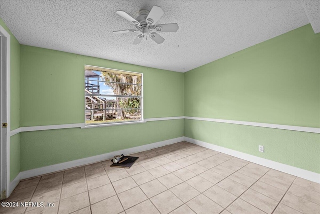 unfurnished room featuring ceiling fan, a textured ceiling, baseboards, and light tile patterned floors