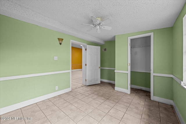 interior space featuring light tile patterned floors, a textured ceiling, a closet, and baseboards