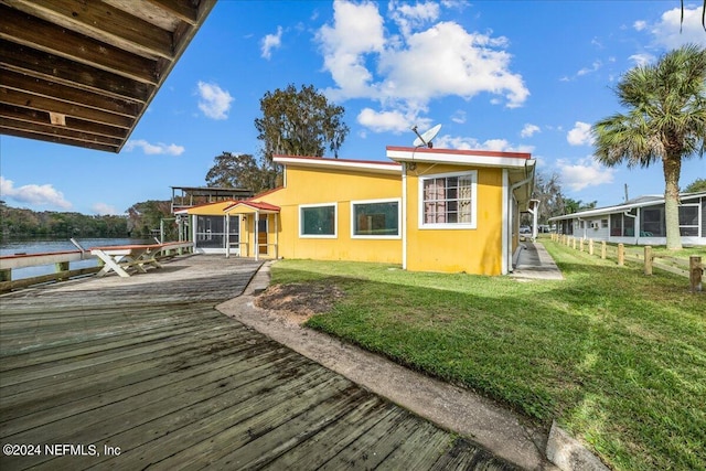 rear view of house with a yard, a water view, and stucco siding