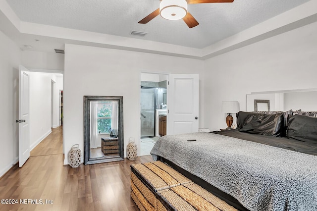 bedroom featuring hardwood / wood-style flooring, ceiling fan, ensuite bathroom, and a textured ceiling