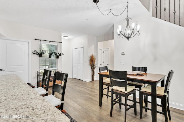 dining room with wood-type flooring, a textured ceiling, and a notable chandelier