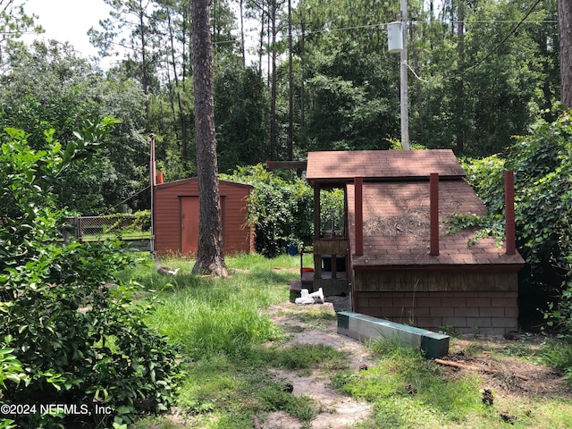 view of yard featuring an outdoor structure, fence, and a storage shed