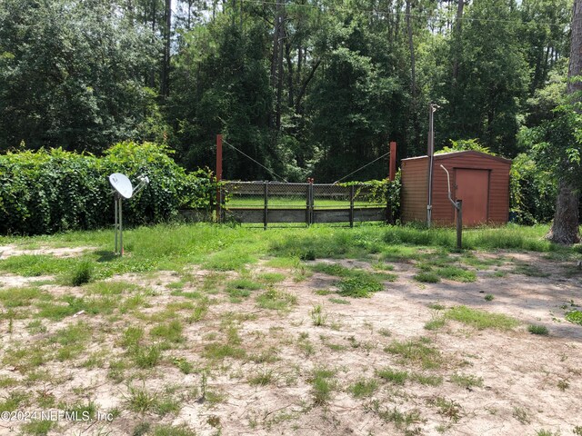 view of yard featuring an outdoor structure, fence, and a storage shed