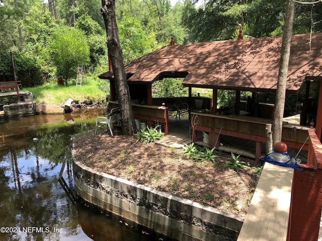 dock area featuring a water view, a wooded view, and a gazebo