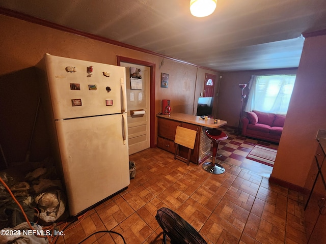 kitchen with tile floors, white refrigerator, and crown molding