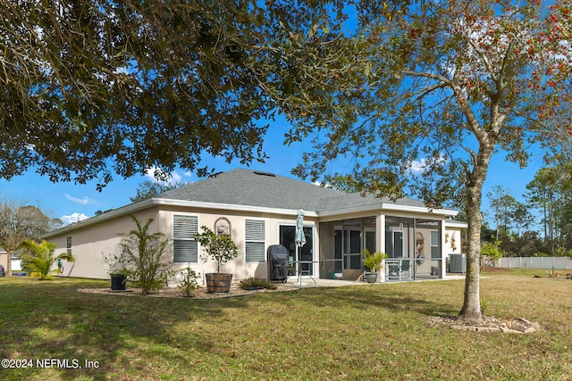 back of property with a lawn, central air condition unit, a sunroom, and a patio