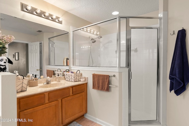 bathroom featuring an enclosed shower, a textured ceiling, tile floors, and vanity with extensive cabinet space