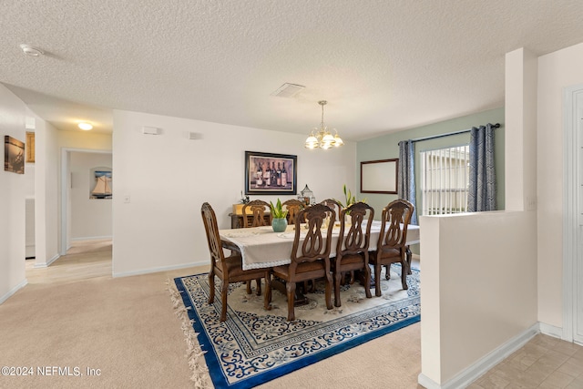 dining room featuring a chandelier, light carpet, and a textured ceiling