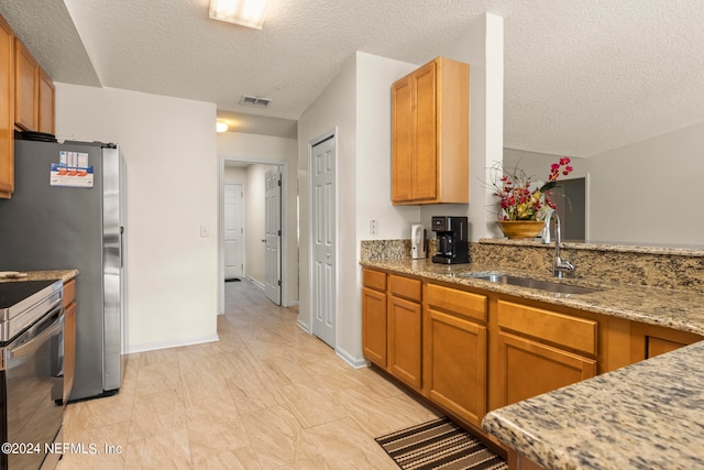 kitchen with light tile flooring, light stone countertops, range, and sink