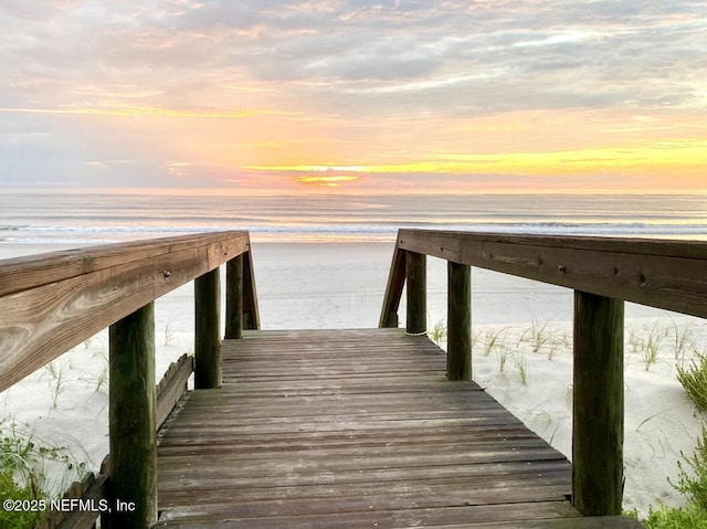 dock area with a water view and a beach view