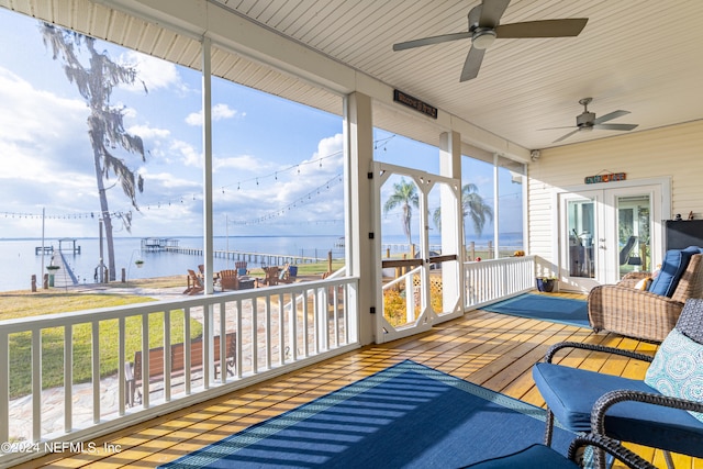 sunroom / solarium featuring french doors, ceiling fan, and a water view