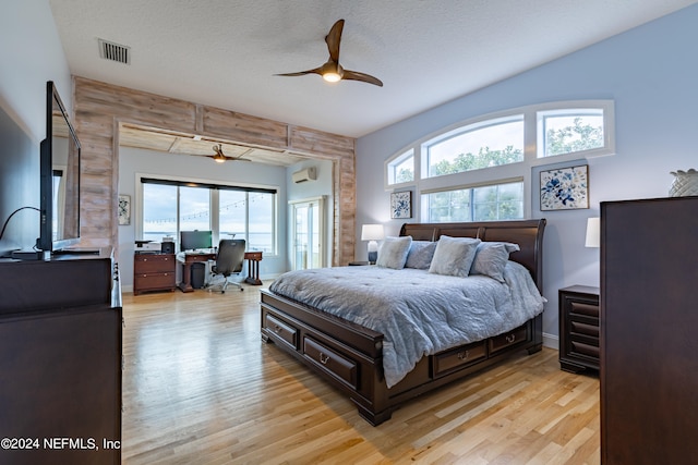 bedroom with wood walls, light hardwood / wood-style flooring, ceiling fan, and a textured ceiling