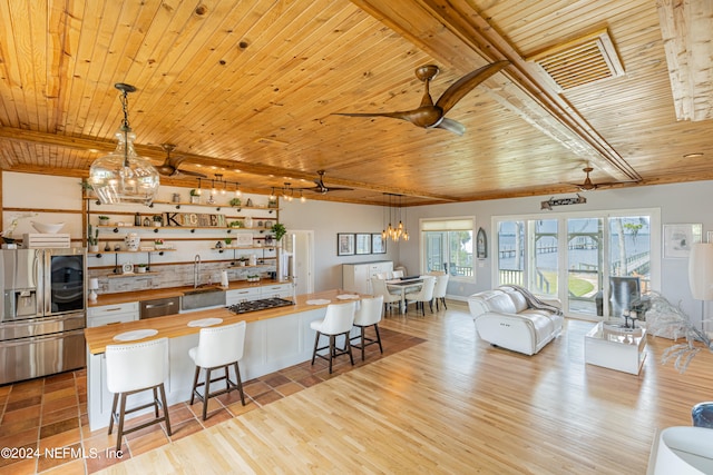 kitchen featuring appliances with stainless steel finishes, a breakfast bar area, wood ceiling, sink, and pendant lighting