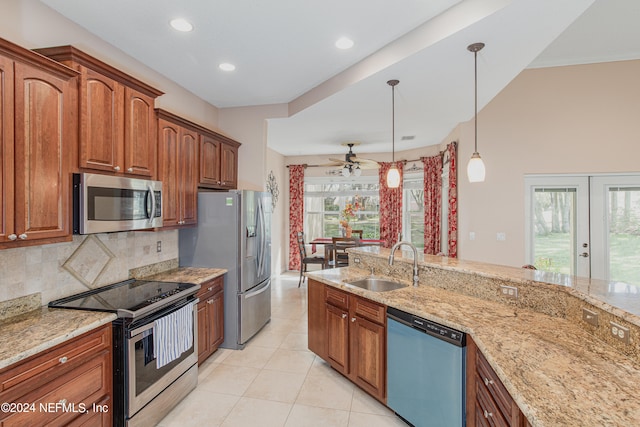 kitchen featuring appliances with stainless steel finishes, light stone counters, ceiling fan, sink, and decorative light fixtures