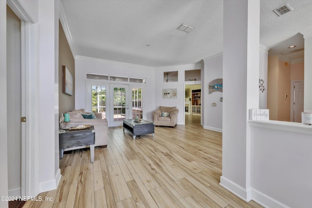 living room featuring french doors, a textured ceiling, light hardwood / wood-style flooring, and ornamental molding