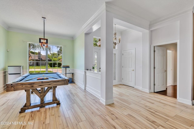 recreation room with crown molding, light wood-type flooring, and a textured ceiling