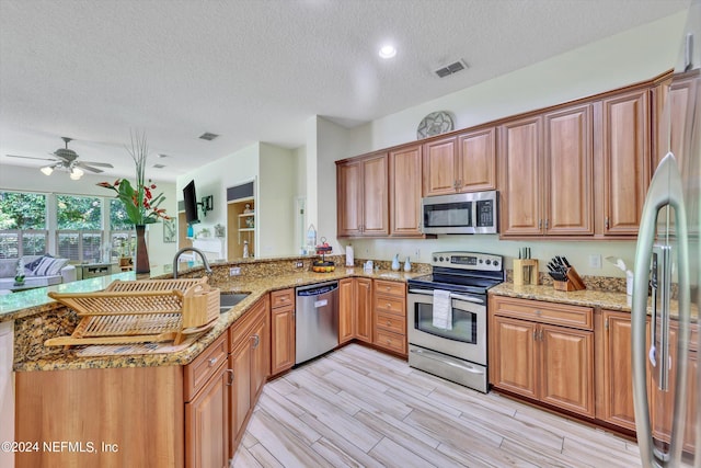 kitchen with ceiling fan, sink, light hardwood / wood-style floors, a textured ceiling, and appliances with stainless steel finishes