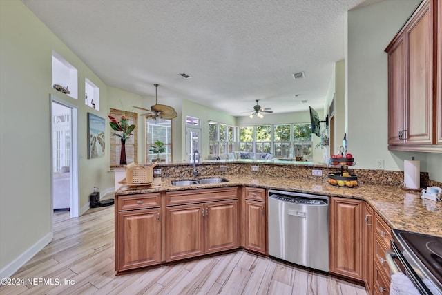 kitchen with sink, light wood-type flooring, stone countertops, kitchen peninsula, and stainless steel appliances