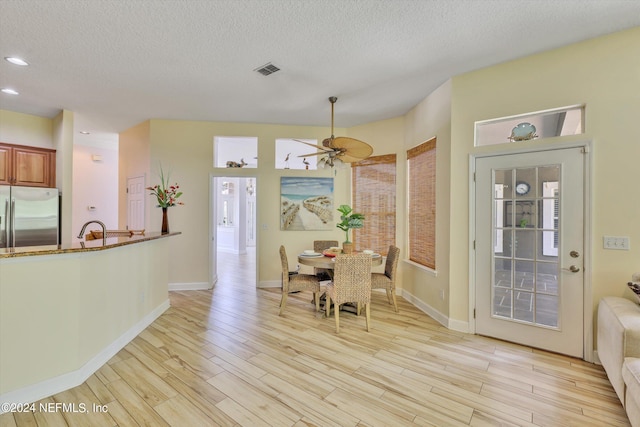 dining area with ceiling fan, light hardwood / wood-style floors, sink, and a textured ceiling