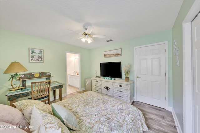 bedroom with a textured ceiling, light hardwood / wood-style floors, ensuite bath, and ceiling fan