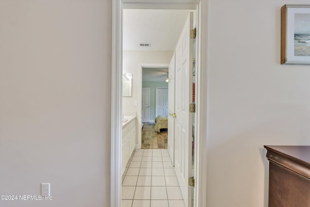 hallway featuring light tile patterned flooring and a textured ceiling