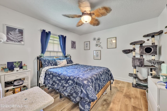 bedroom with ceiling fan, light hardwood / wood-style flooring, and a textured ceiling