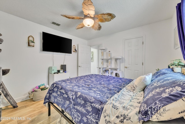 bedroom with hardwood / wood-style flooring, ceiling fan, and a textured ceiling