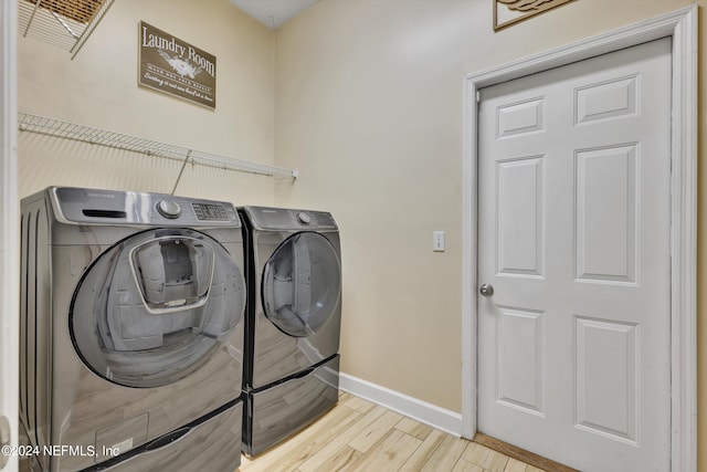 laundry area with washing machine and dryer and light hardwood / wood-style flooring