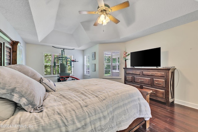 bedroom with a textured ceiling, ceiling fan, dark wood-type flooring, and multiple windows