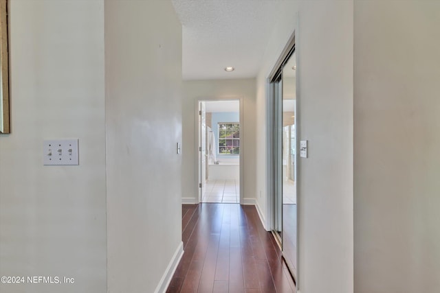 hall featuring a textured ceiling and dark wood-type flooring