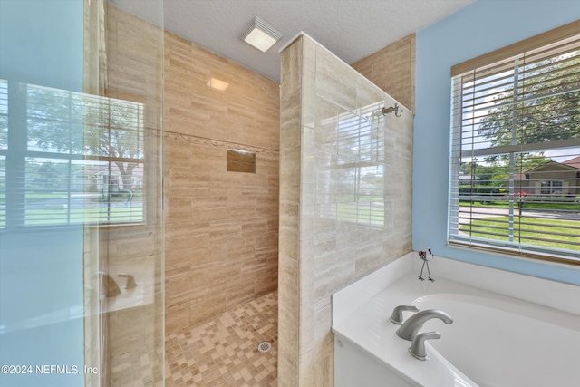 bathroom featuring a textured ceiling and independent shower and bath