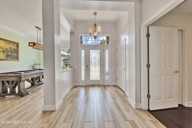 foyer entrance with a notable chandelier, light hardwood / wood-style floors, and ornamental molding